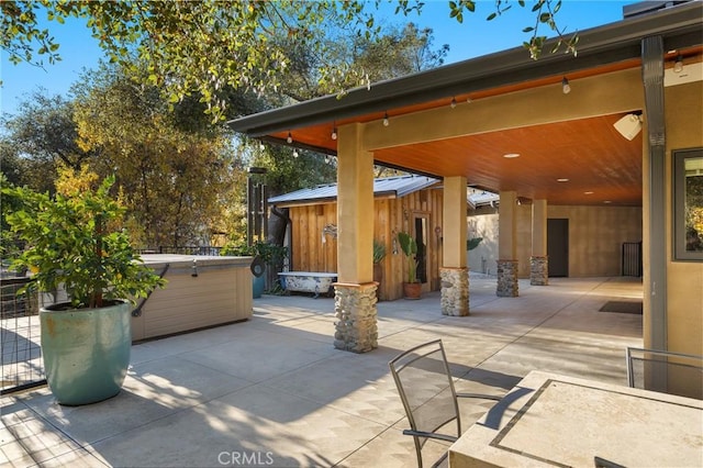 view of patio with a hot tub and a storage shed