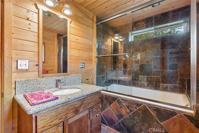 bathroom featuring vanity, wood walls, combined bath / shower with glass door, and wooden ceiling