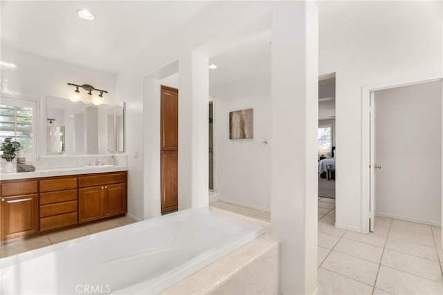 bathroom with vanity, tiled bath, and tile patterned flooring