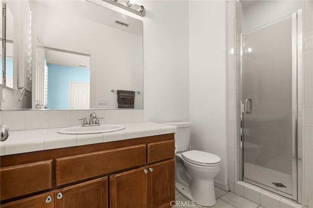 bathroom with vanity, toilet, tile patterned flooring, and a shower with door