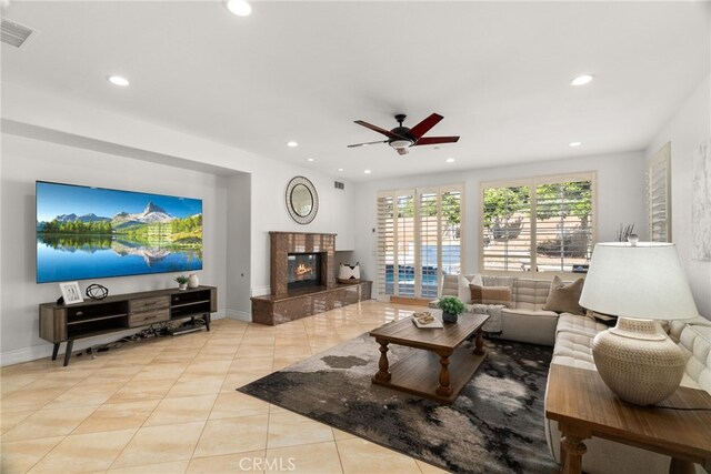 tiled living room with a fireplace and ceiling fan