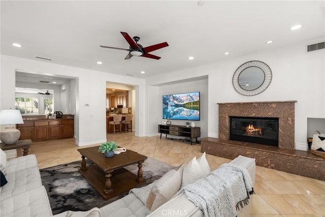 living room with ceiling fan, light tile patterned floors, and a high end fireplace