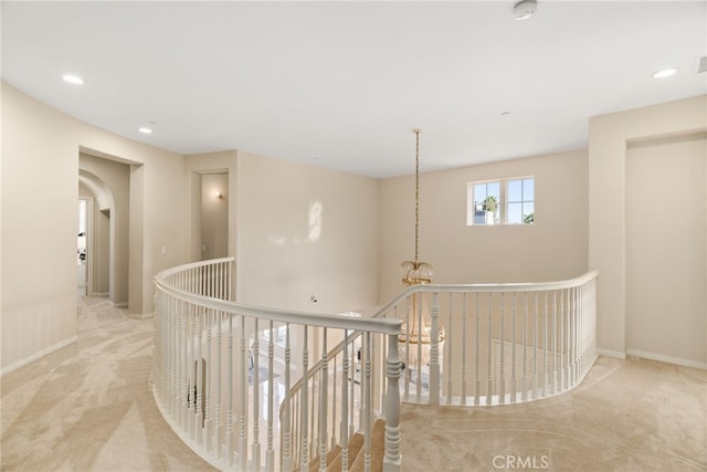 hall featuring an inviting chandelier and light colored carpet