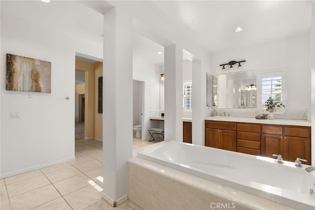 bathroom with tiled bath, toilet, tile patterned flooring, a bidet, and vanity