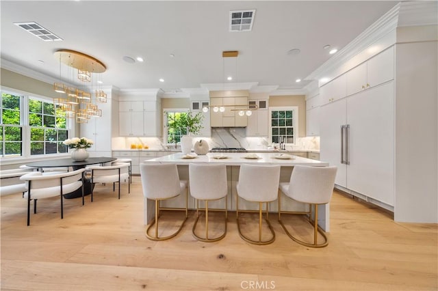 kitchen with white cabinets, pendant lighting, tasteful backsplash, and light hardwood / wood-style flooring