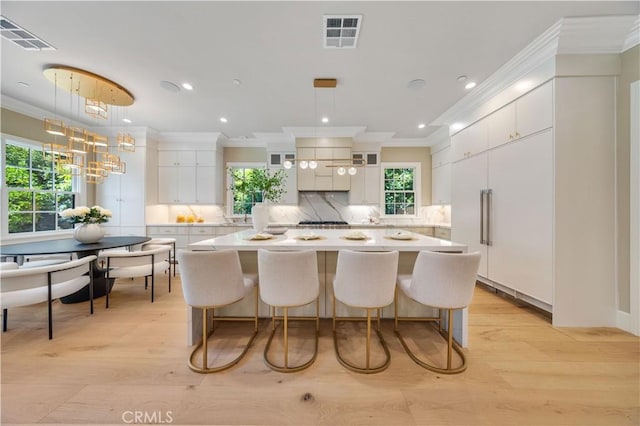 kitchen featuring a healthy amount of sunlight, white cabinets, hanging light fixtures, and light hardwood / wood-style floors