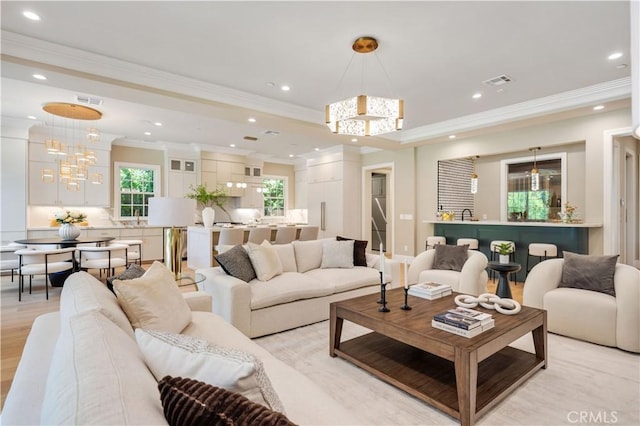 living room featuring ornamental molding, a chandelier, and light hardwood / wood-style floors