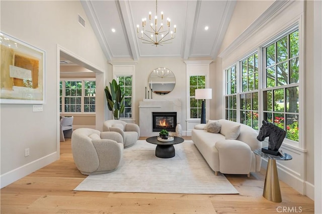 living room with a wealth of natural light, high vaulted ceiling, a chandelier, and light wood-type flooring