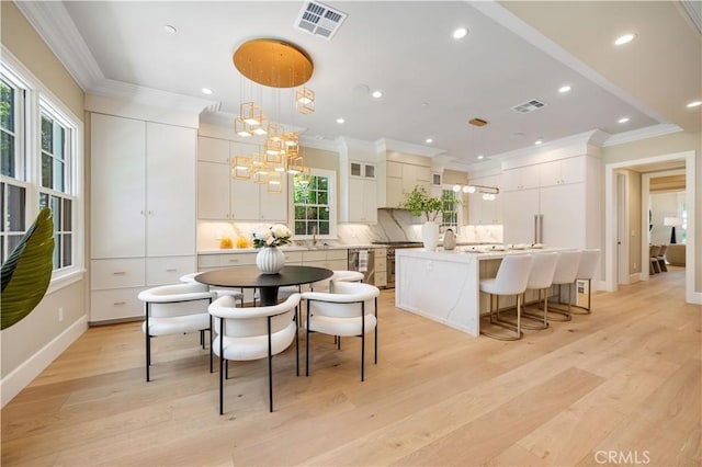 dining space with light hardwood / wood-style flooring, a wealth of natural light, and crown molding