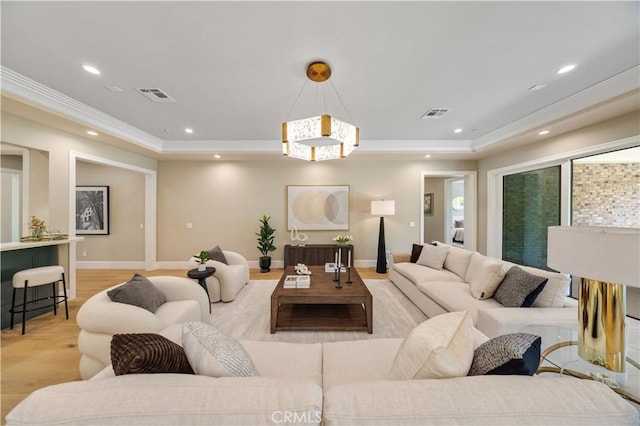 living room featuring light hardwood / wood-style flooring, a chandelier, and ornamental molding