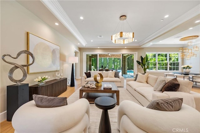 living room with a notable chandelier, ornamental molding, and light hardwood / wood-style flooring