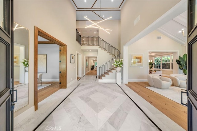 foyer entrance with beamed ceiling, a notable chandelier, high vaulted ceiling, and light hardwood / wood-style flooring