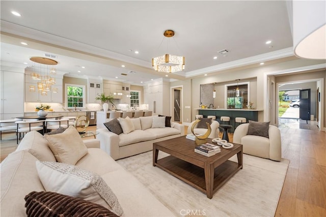 living room with light hardwood / wood-style flooring, ornamental molding, and a notable chandelier