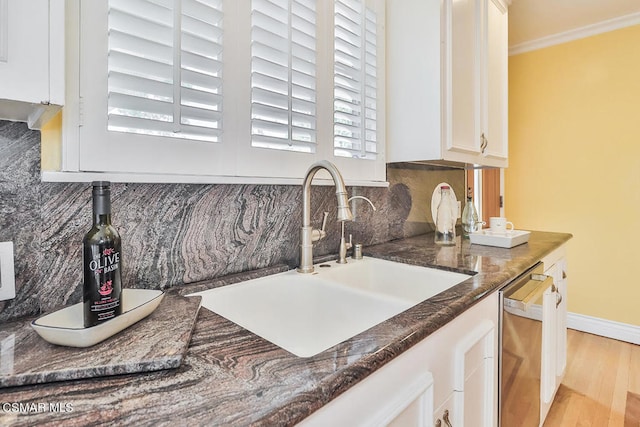 kitchen featuring sink, light hardwood / wood-style floors, stainless steel dishwasher, white cabinetry, and ornamental molding