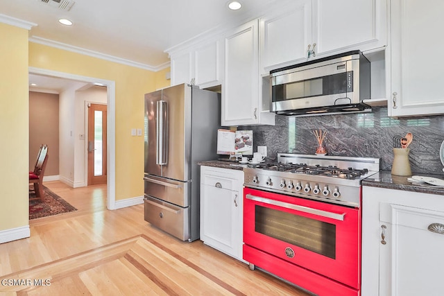 kitchen with decorative backsplash, stainless steel appliances, light hardwood / wood-style floors, and white cabinets