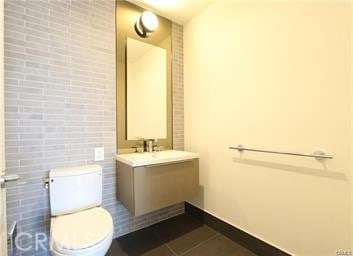 bathroom with tile patterned flooring, vanity, toilet, and tile walls