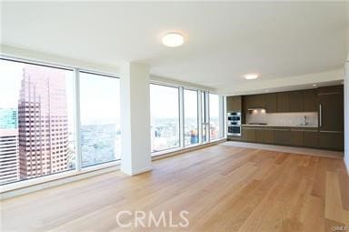 unfurnished living room featuring a wall of windows and light wood-type flooring