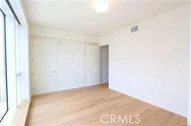 unfurnished bedroom with light wood-type flooring and a closet