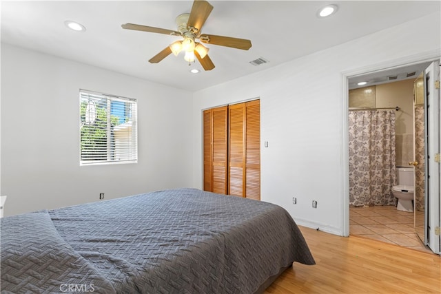 bedroom featuring ensuite bath, ceiling fan, a closet, and hardwood / wood-style flooring