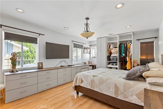 bedroom featuring a closet, light hardwood / wood-style floors, and multiple windows