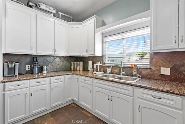 kitchen with decorative backsplash, dark stone countertops, white cabinetry, and sink