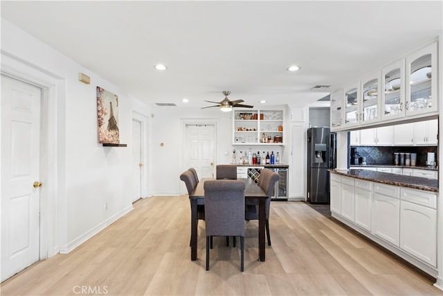 dining room with ceiling fan, bar area, and light hardwood / wood-style flooring