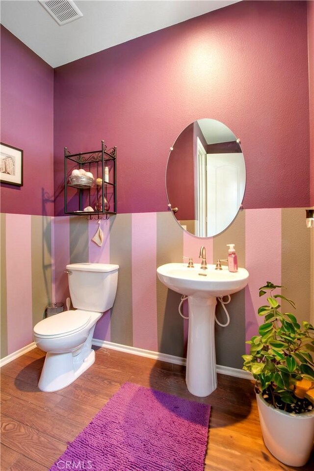 bathroom with wood-type flooring, toilet, and sink