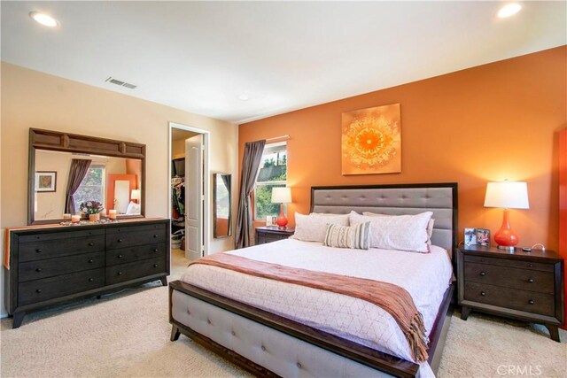 carpeted bedroom with multiple windows, a walk in closet, and a closet