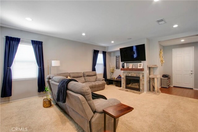 living room with a healthy amount of sunlight, light hardwood / wood-style floors, and a tile fireplace