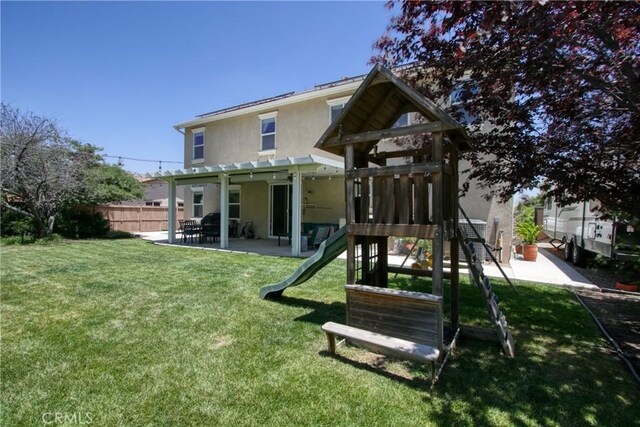 back of property with a patio, a playground, and a lawn