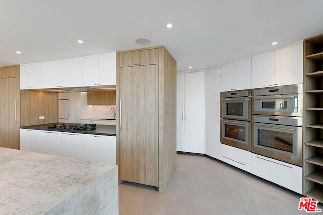 kitchen featuring stainless steel appliances, sink, light brown cabinets, light tile patterned floors, and white cabinetry