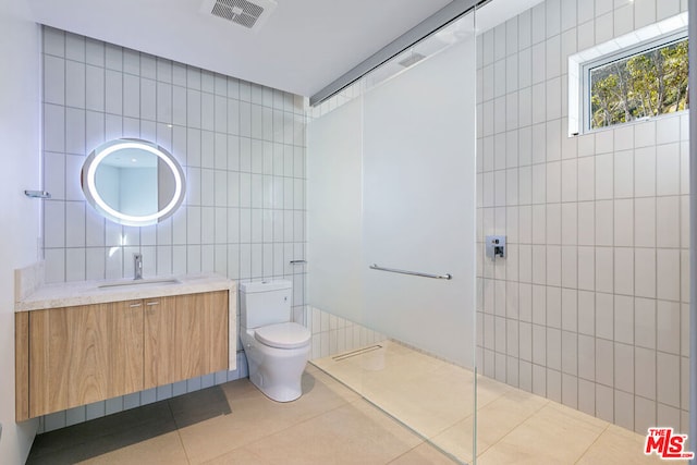 bathroom with vanity, a shower, tile walls, tile patterned flooring, and toilet