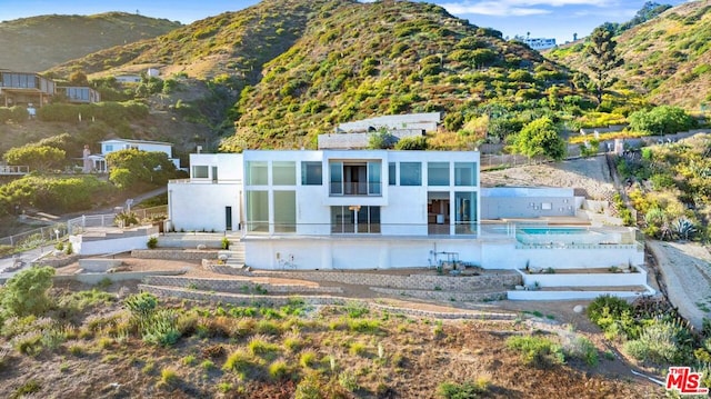 rear view of property featuring a mountain view and a balcony