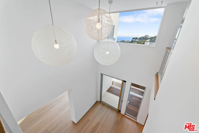 interior space with a towering ceiling, light hardwood / wood-style floors, and an inviting chandelier