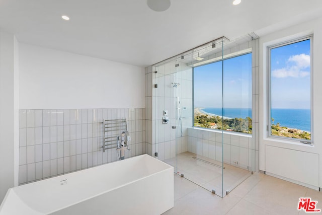 bathroom featuring tile patterned flooring, a water view, and independent shower and bath