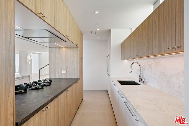 kitchen with backsplash, dark stone countertops, light tile patterned floors, and sink