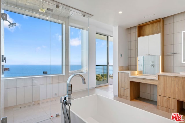 bathroom with a water view, tile patterned floors, plenty of natural light, and a tub