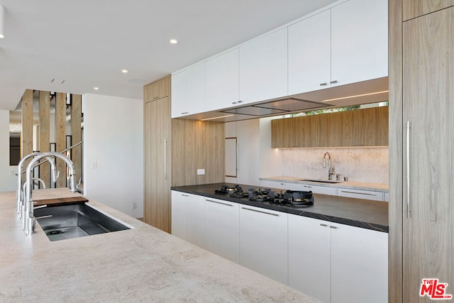 kitchen with backsplash, sink, and white cabinets