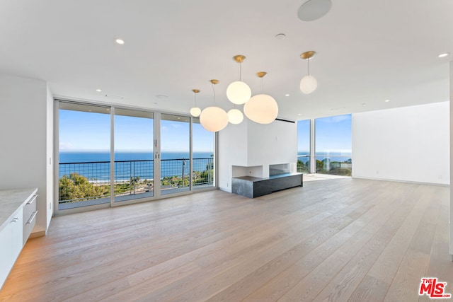 unfurnished living room featuring expansive windows, a wealth of natural light, light hardwood / wood-style flooring, and a water view