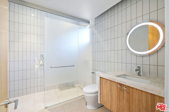 bathroom with tile patterned floors, vanity, a shower, tile walls, and toilet