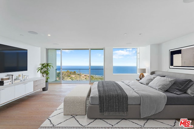 bedroom with access to exterior, light wood-type flooring, a water view, and expansive windows