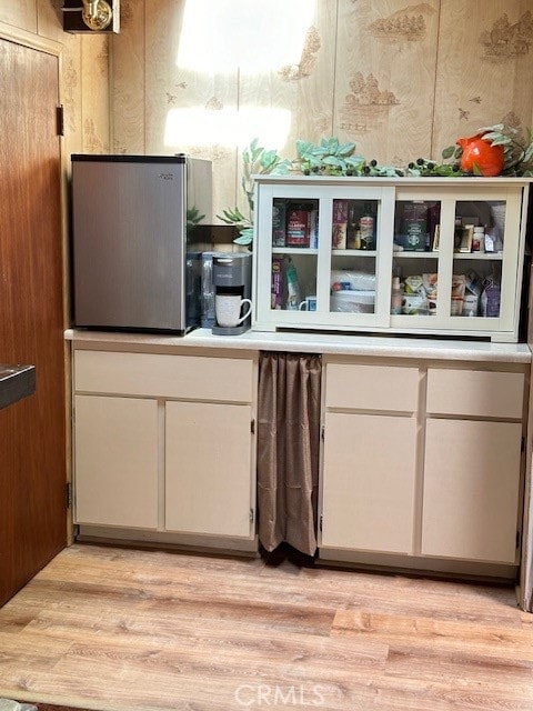 kitchen featuring wooden walls, light hardwood / wood-style flooring, and white cabinetry