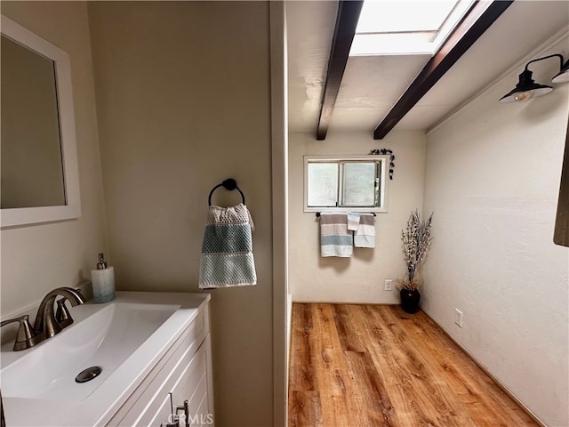 clothes washing area featuring light hardwood / wood-style flooring, a skylight, and sink