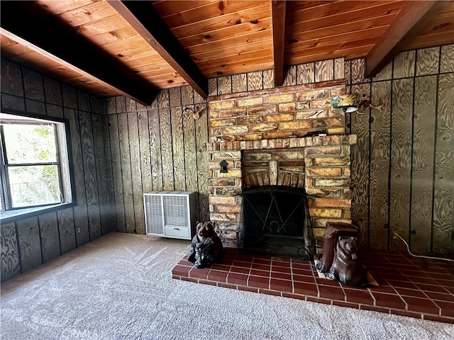 unfurnished living room featuring wooden walls, wood ceiling, dark colored carpet, a fireplace, and beam ceiling