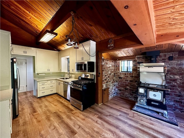 kitchen featuring sink, brick wall, white cabinetry, stainless steel appliances, and light hardwood / wood-style floors