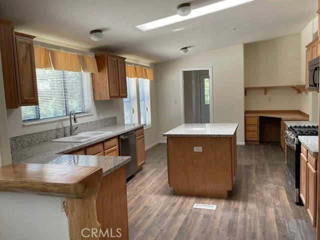41501 Island Dr, Forest Falls, CA 92339 - kitchen with a peninsula, a center island, a sink, wood finished floors, and appliances with stainless steel finishes