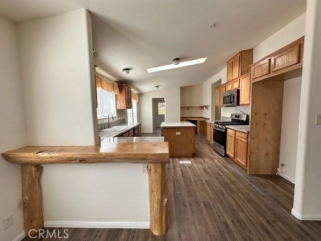 41501 Island Dr, Forest Falls, CA 92339 - kitchen featuring a sink, brown cabinetry, a peninsula, appliances with stainless steel finishes, and a kitchen island