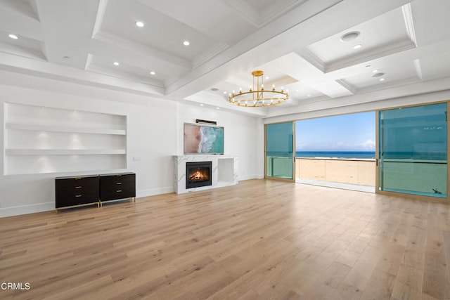 unfurnished living room with light hardwood / wood-style floors, coffered ceiling, beamed ceiling, a chandelier, and a premium fireplace