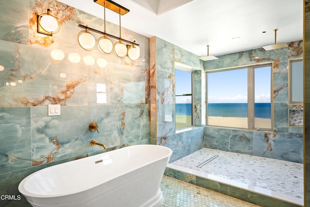 bathroom with independent shower and bath, tile walls, tile patterned flooring, and a water view