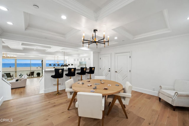 dining area featuring an inviting chandelier, light hardwood / wood-style flooring, ornamental molding, and a water view